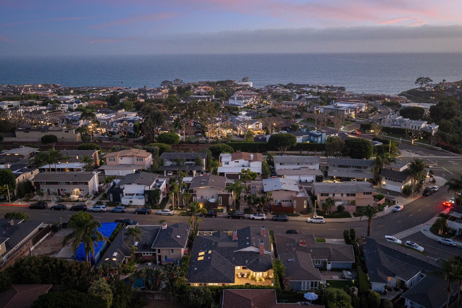 Corona del Mar neighborhood rooftops around 433 Seaward Road, with the ocean in the distance at dusk