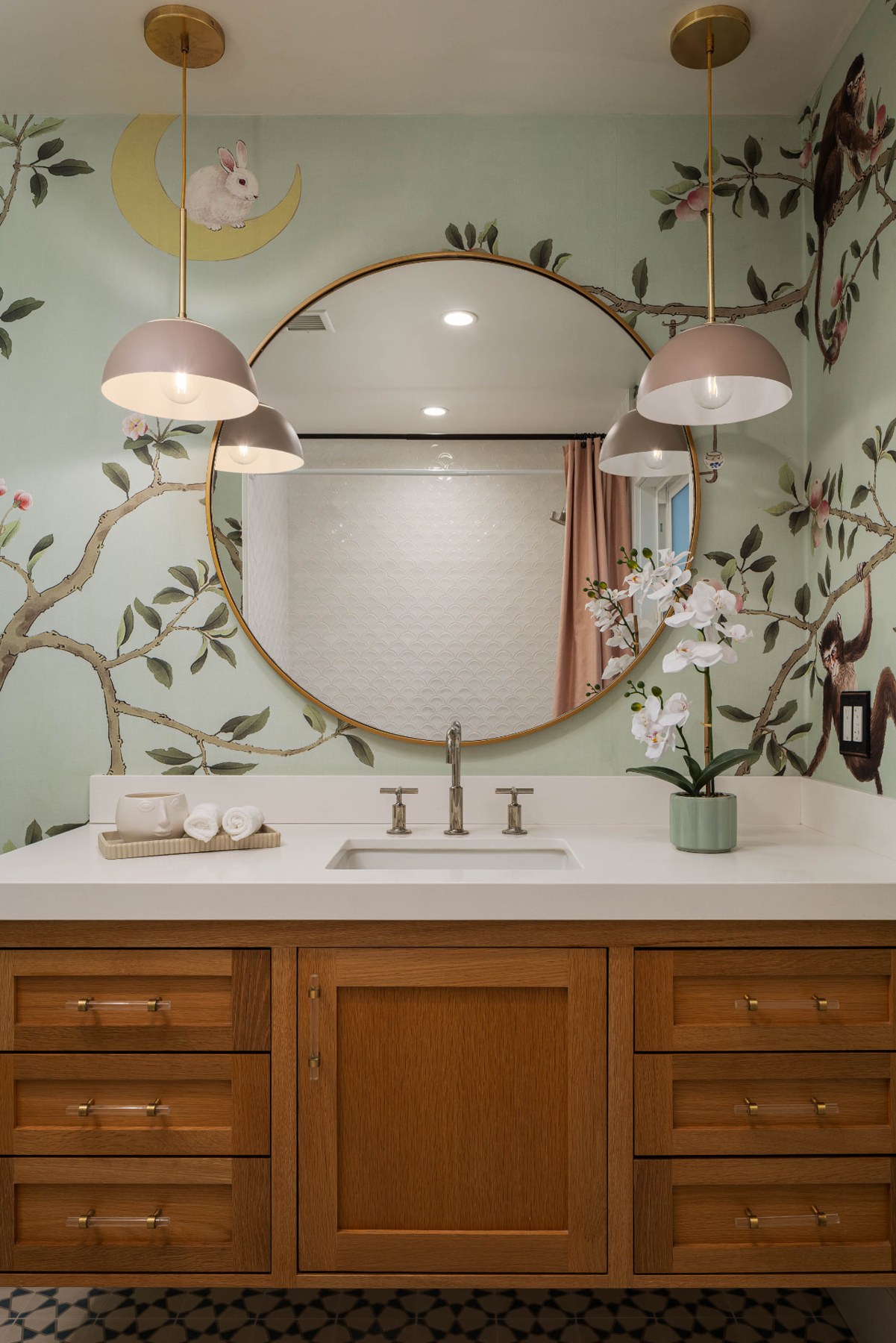 Bathroom vanity at 433 Seaward Road with wood cabinetry, a round mirror and botanical wallpaper