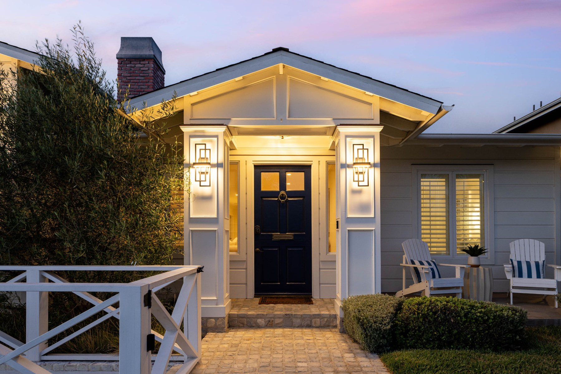 Illuminated front door at 433 Seaward Road, with a pitched porch roof and white railings